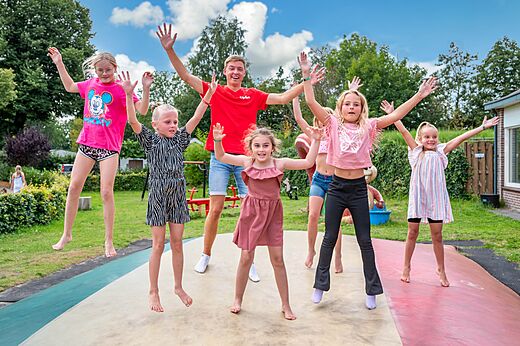 Kinder und Animateur springen auf einem Riesentrampolin auf dem Campingplatz CAPFUN Zeumersehof in Voorthuizen.