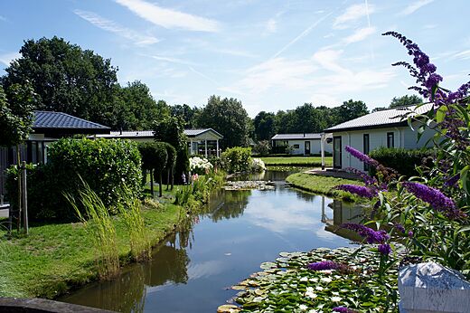 Moderne Mobilheime am blühenden Kanal auf dem Campingplatz CAPFUN Zeumersehof in Voorthuizen.