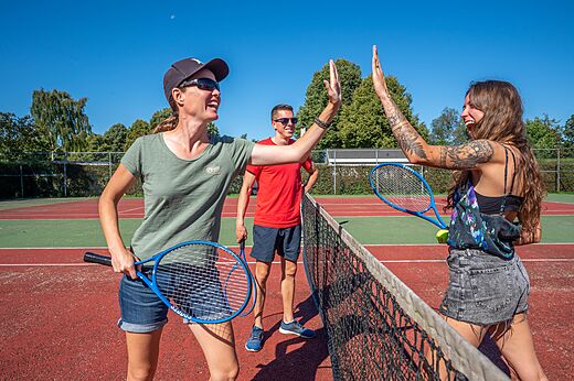 Tennisspieler geben sich High-five auf dem Tennisplatz im Camping CAPFUN Zeumersehof in Voorthuizen.