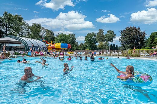Außenpool mit Wasserrutschen und Badegästen auf dem Campingplatz CAPFUN Zeumersehof in Voorthuizen.