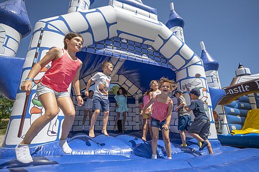 Kinder springen auf einer blau-weißen Hüpfburg auf dem Campingplatz CAPFUN Zeumersehof in Voorthuizen.